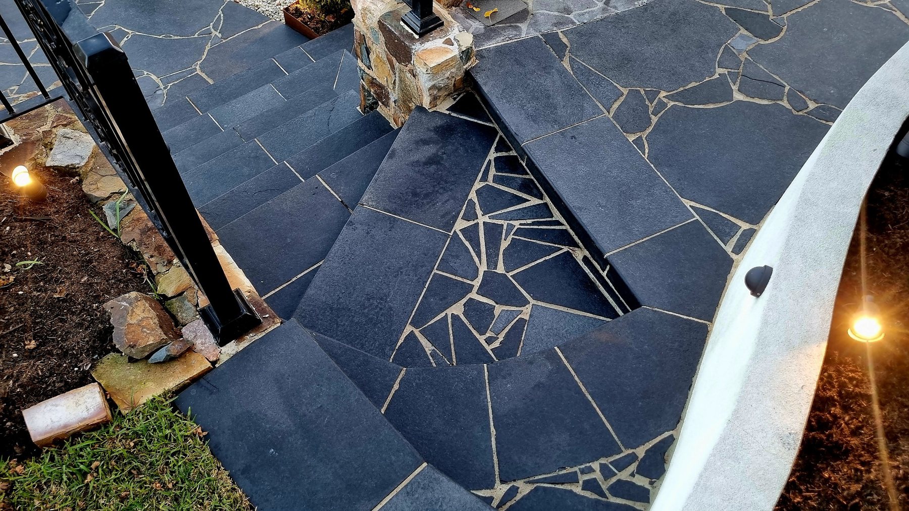 Turning black stone steps with hand-cut crazy paving filling the corner