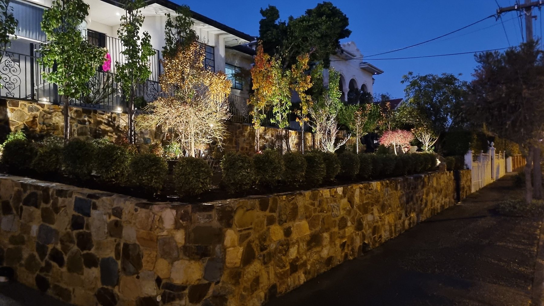 Natural stone front wall and terraced planting lit up at night