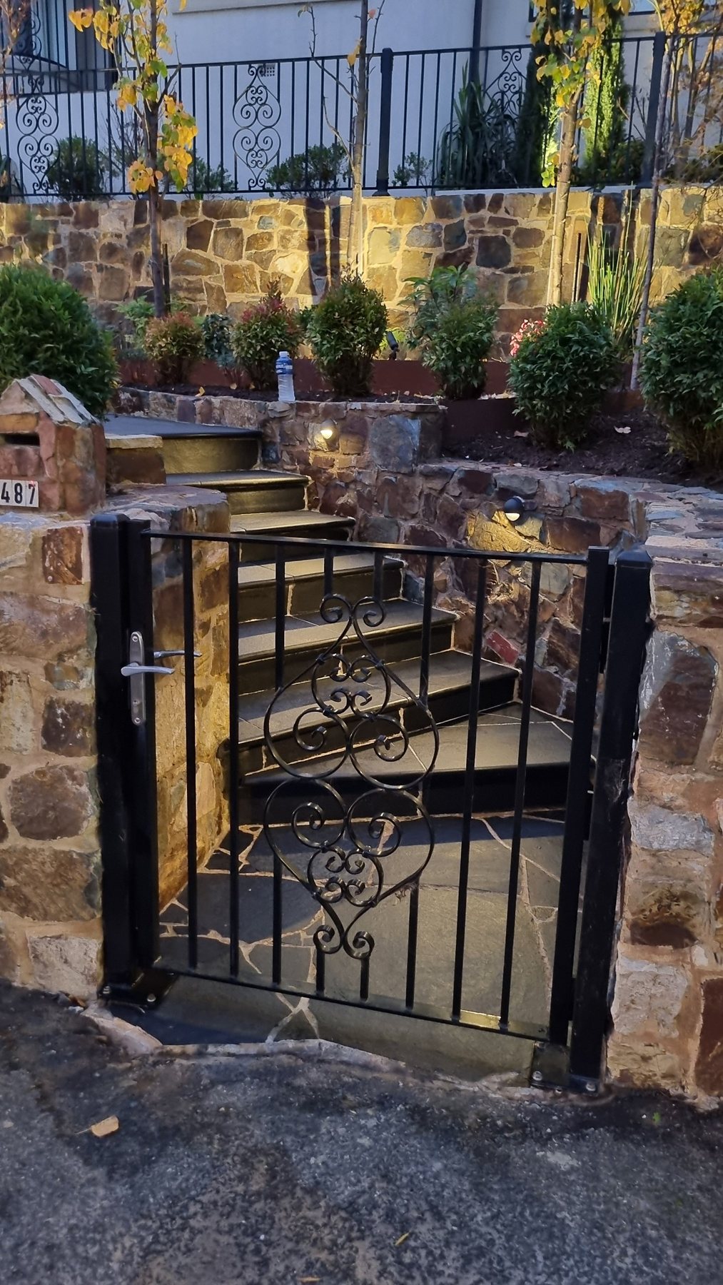 Iron gate opening onto lit black stone steps between stone walls