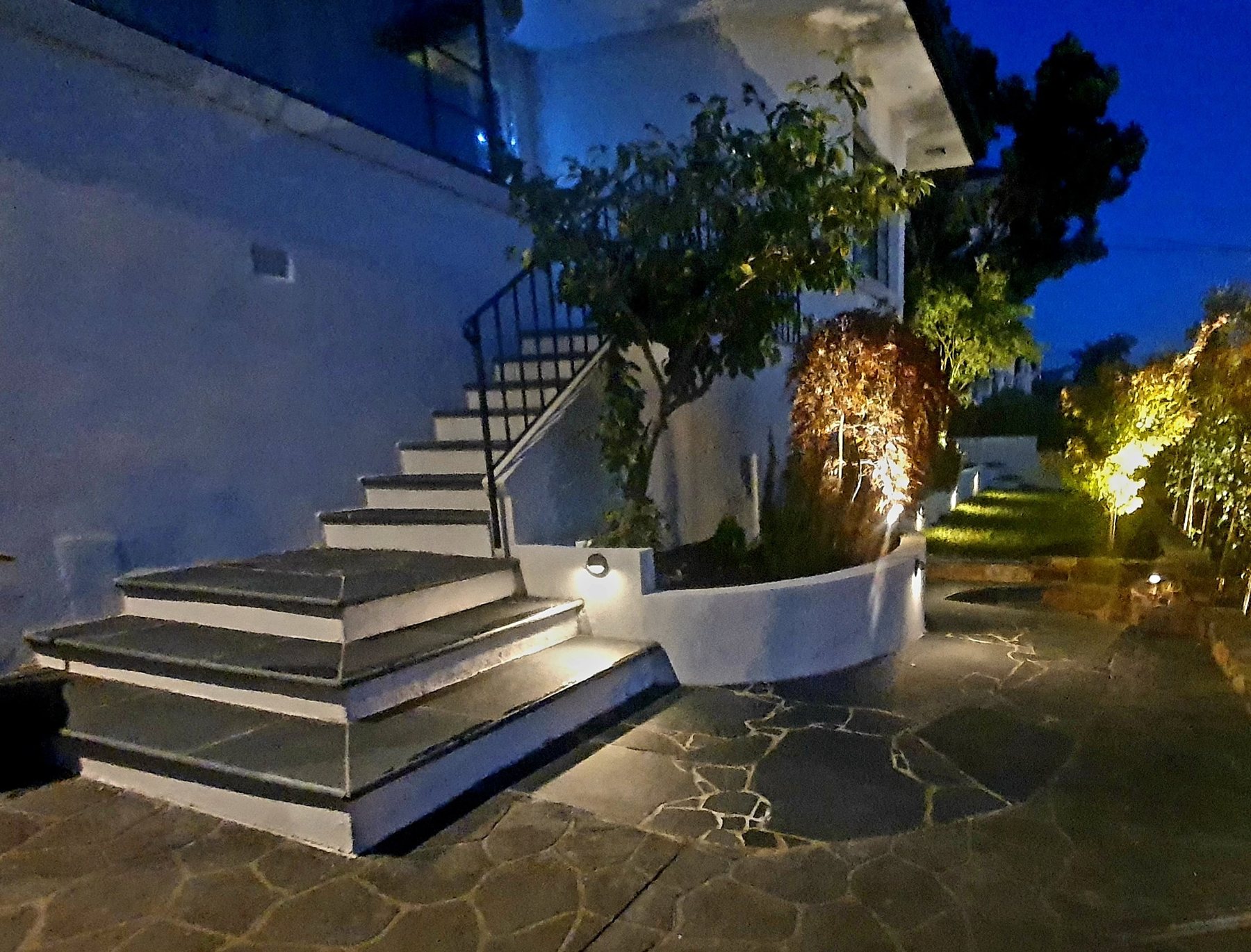White rendered steps and curved planter lit at night