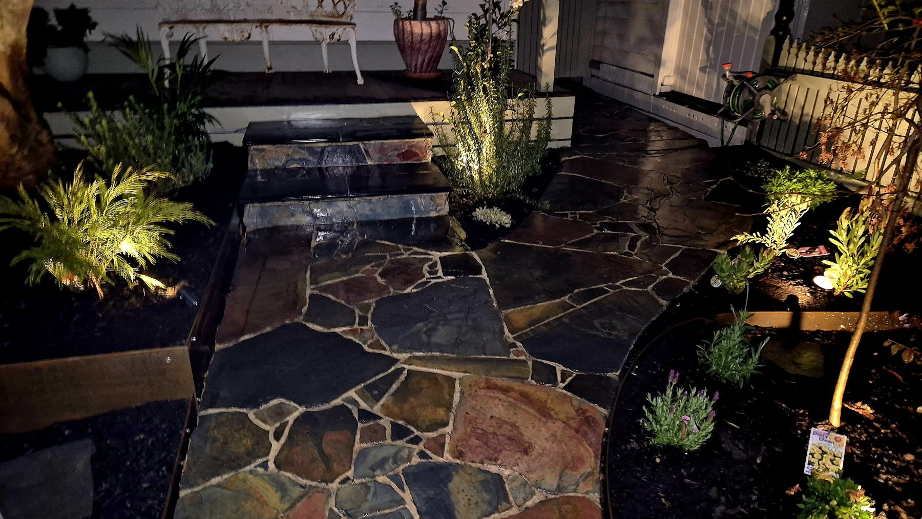 Multicoloured slate crazy paving path and steps lit at night