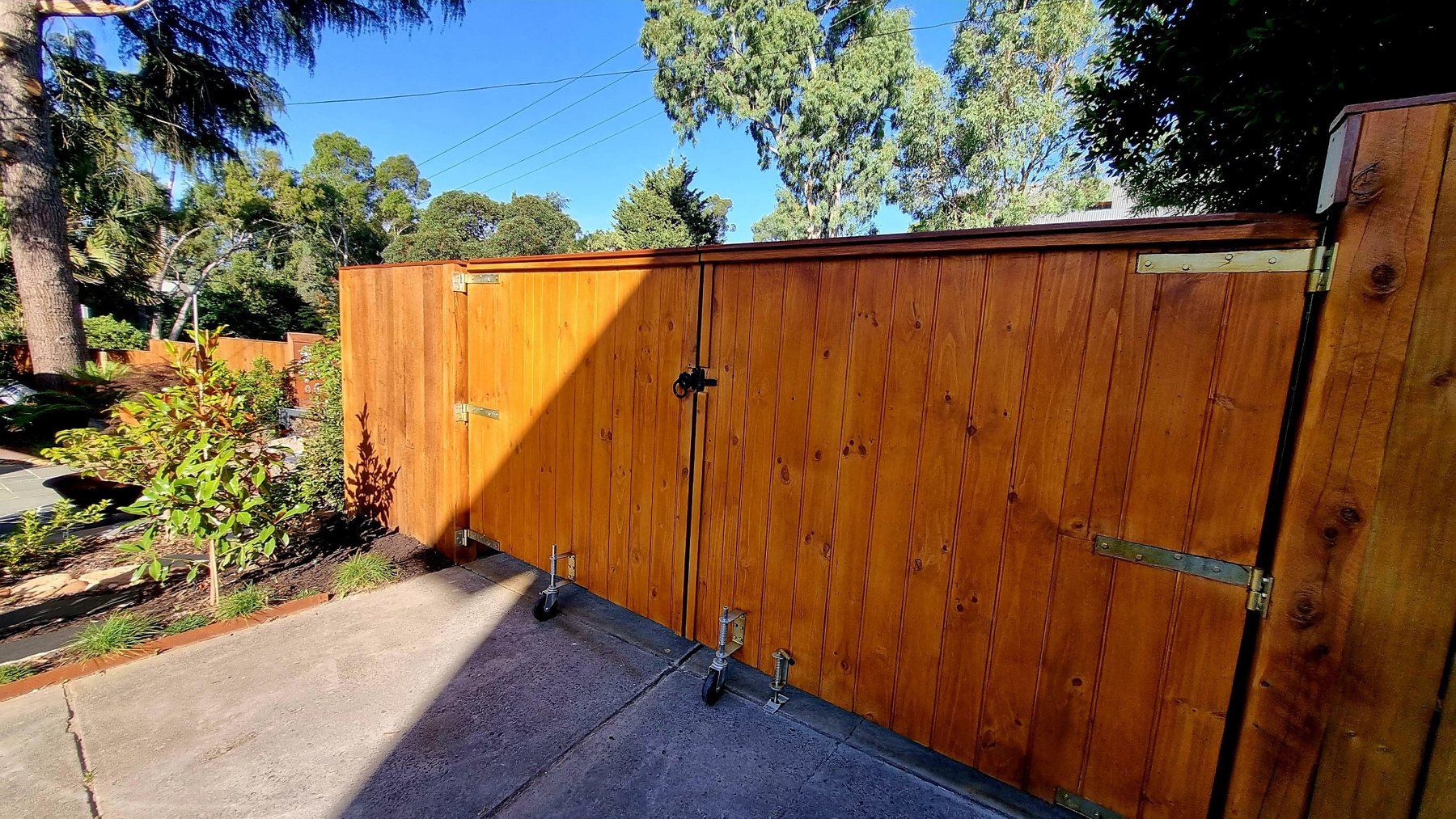 Stained timber double gates with heavy hinges and gate wheels