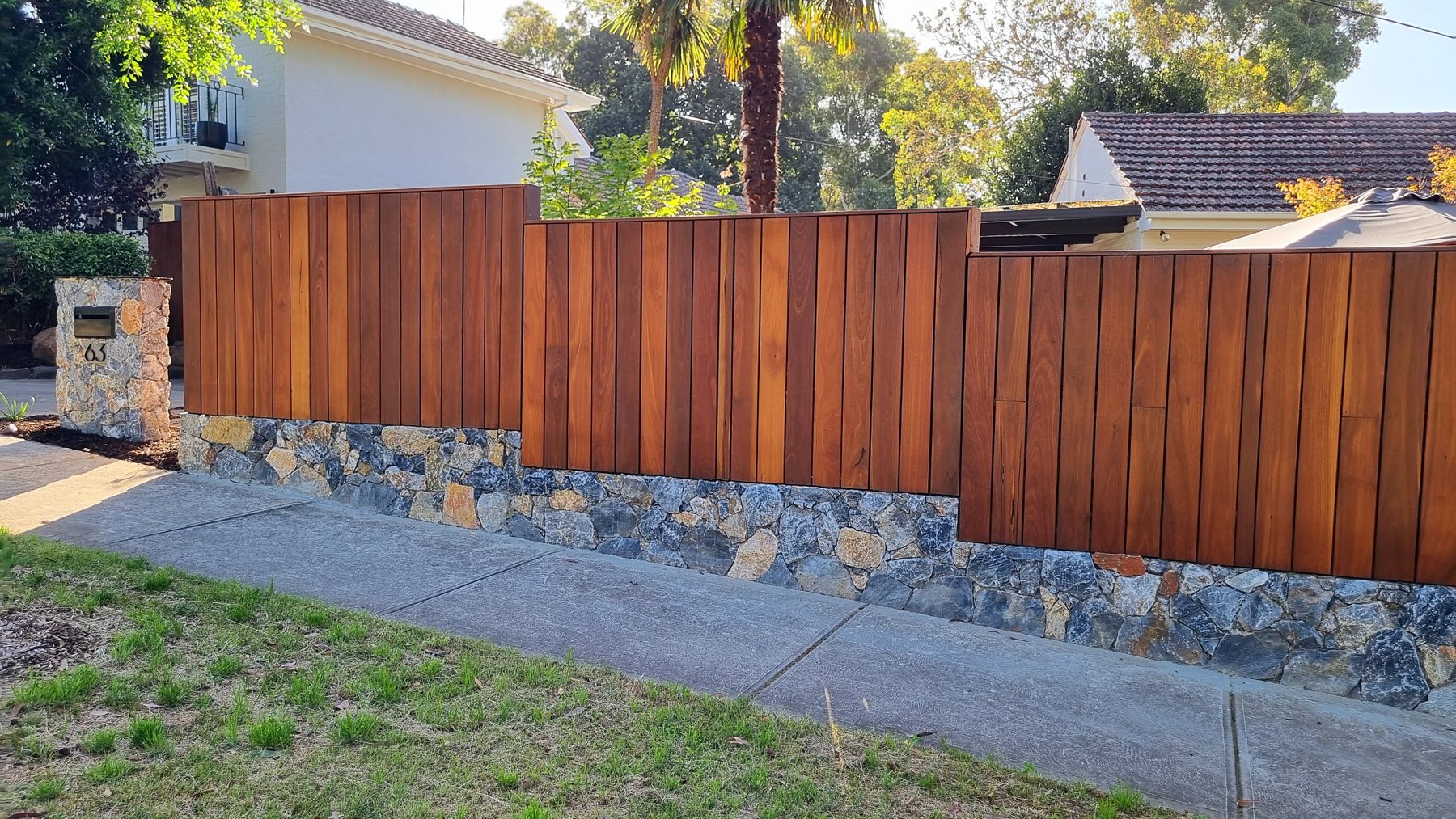 Hardwood fence over a stone plinth beside a natural stone letterbox pillar