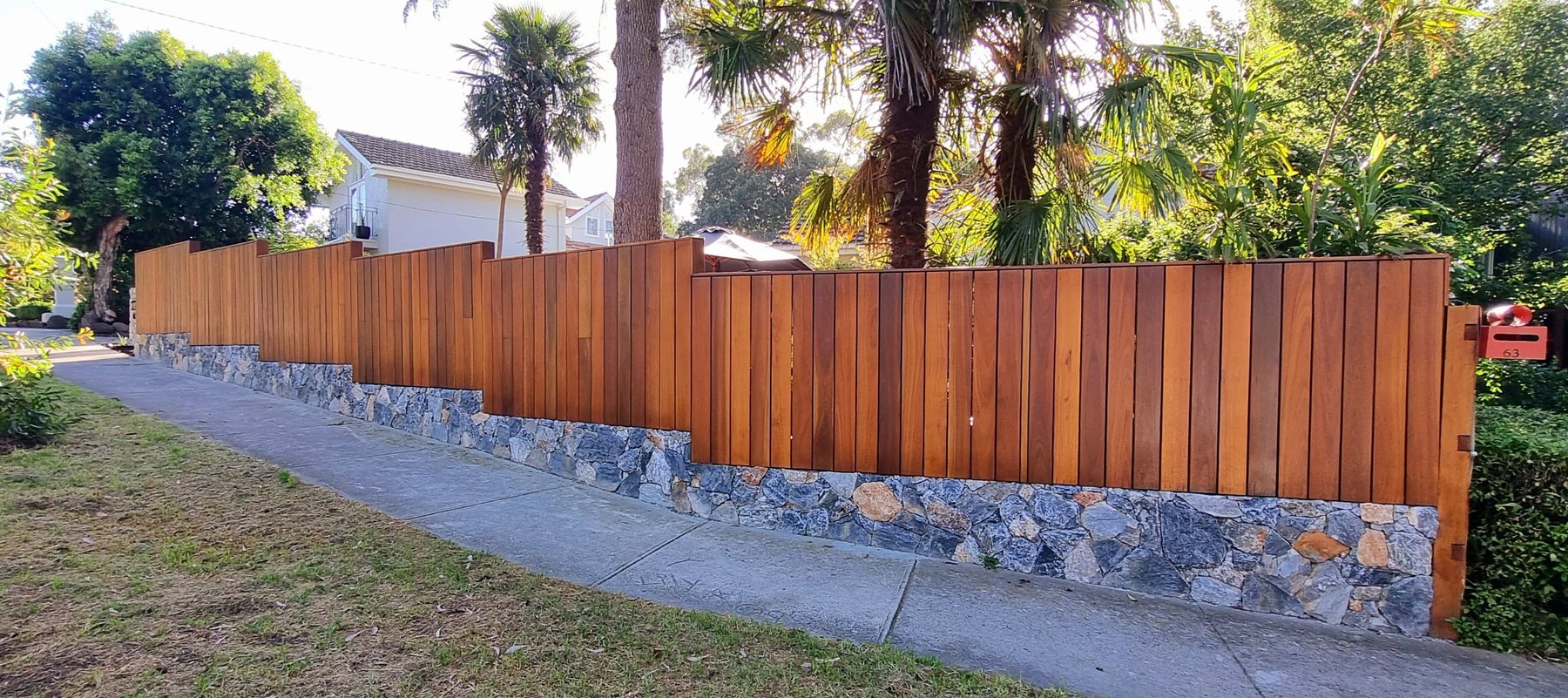 Long hardwood batten fence and stone plinth along the street
