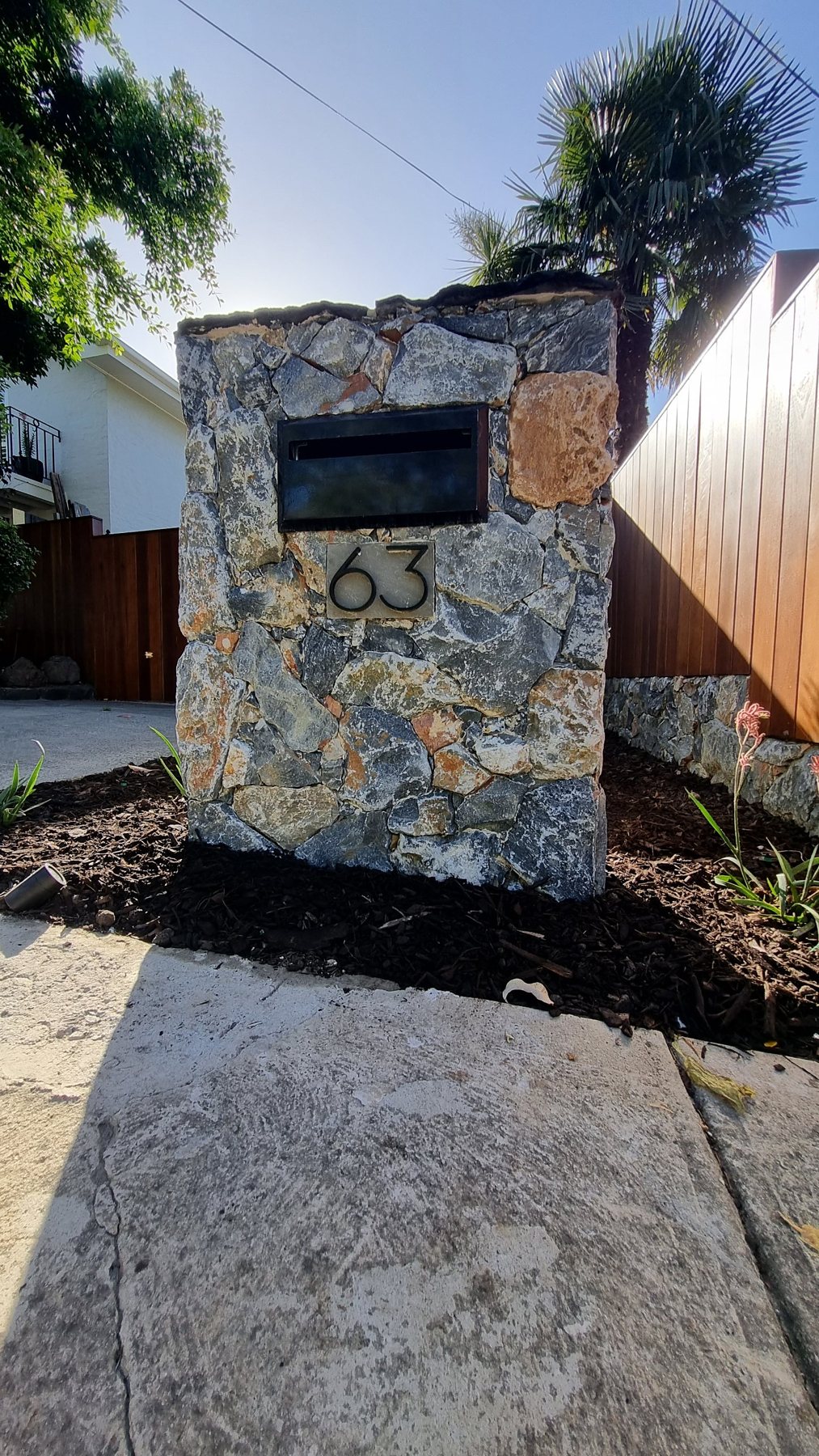 Natural stone letterbox pillar with black letterbox and house number