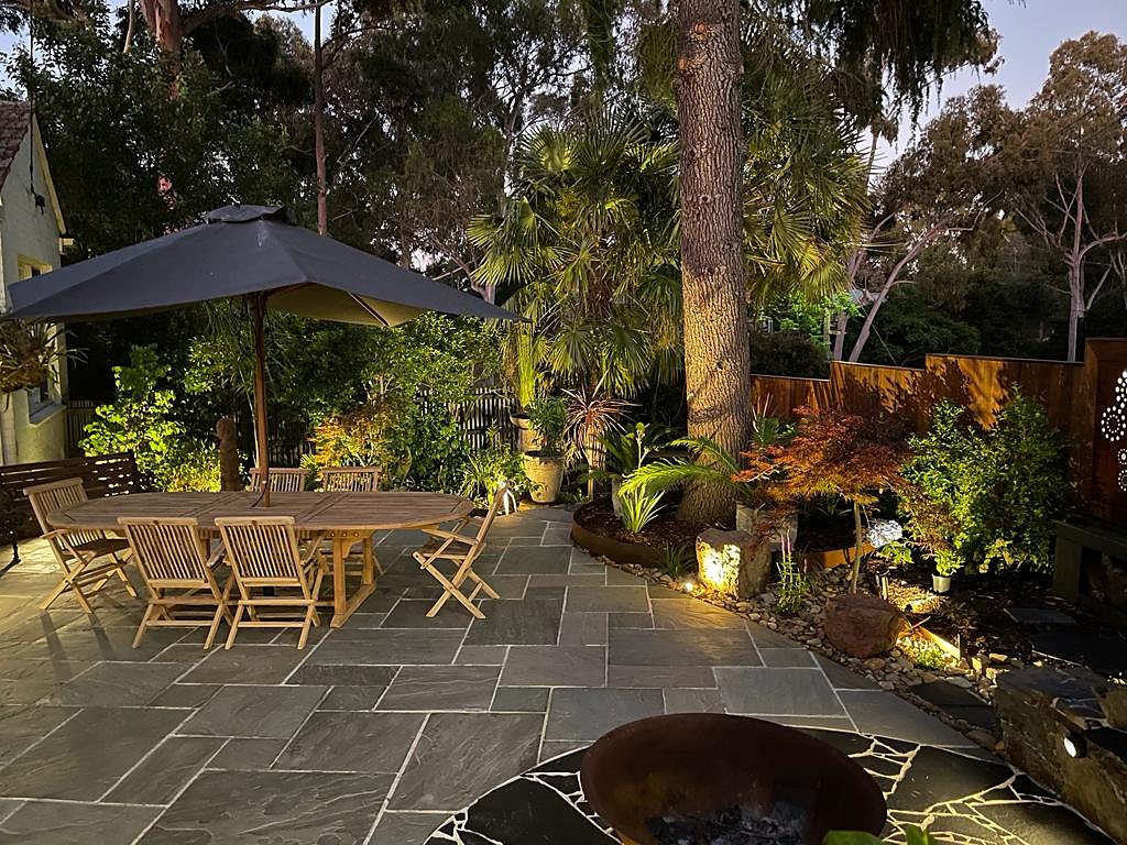 Dining terrace, uplit boulders and palms at dusk
