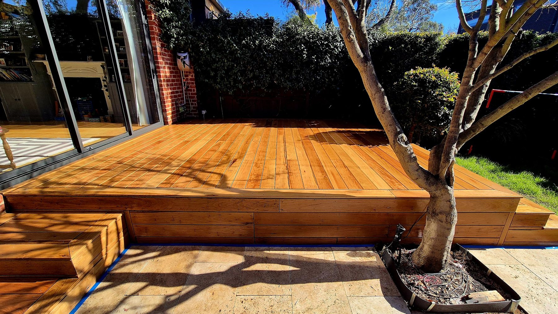 Wide view of the oiled hardwood deck with its boxed fascia and tree surround