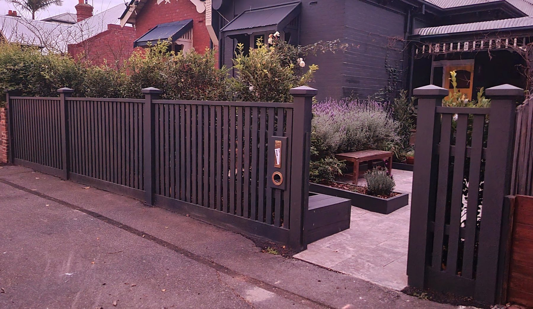 Charcoal timber front fence and gate with travertine paving and lavender beds
