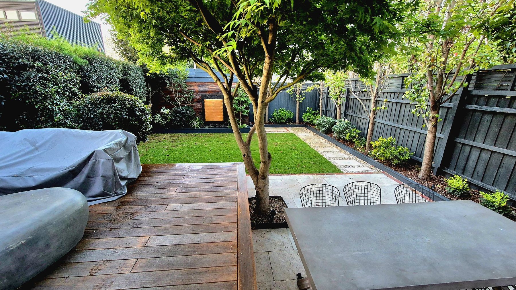 View from the deck across the travertine dining area to the lawn and stepping stones