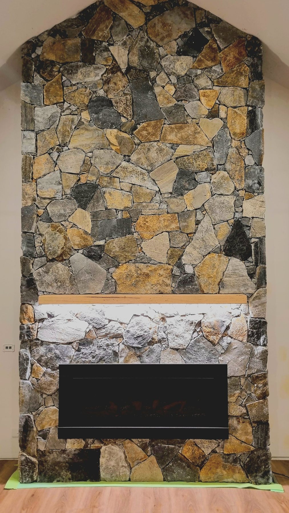 Full-height natural stone fireplace with a lit timber mantel above the firebox