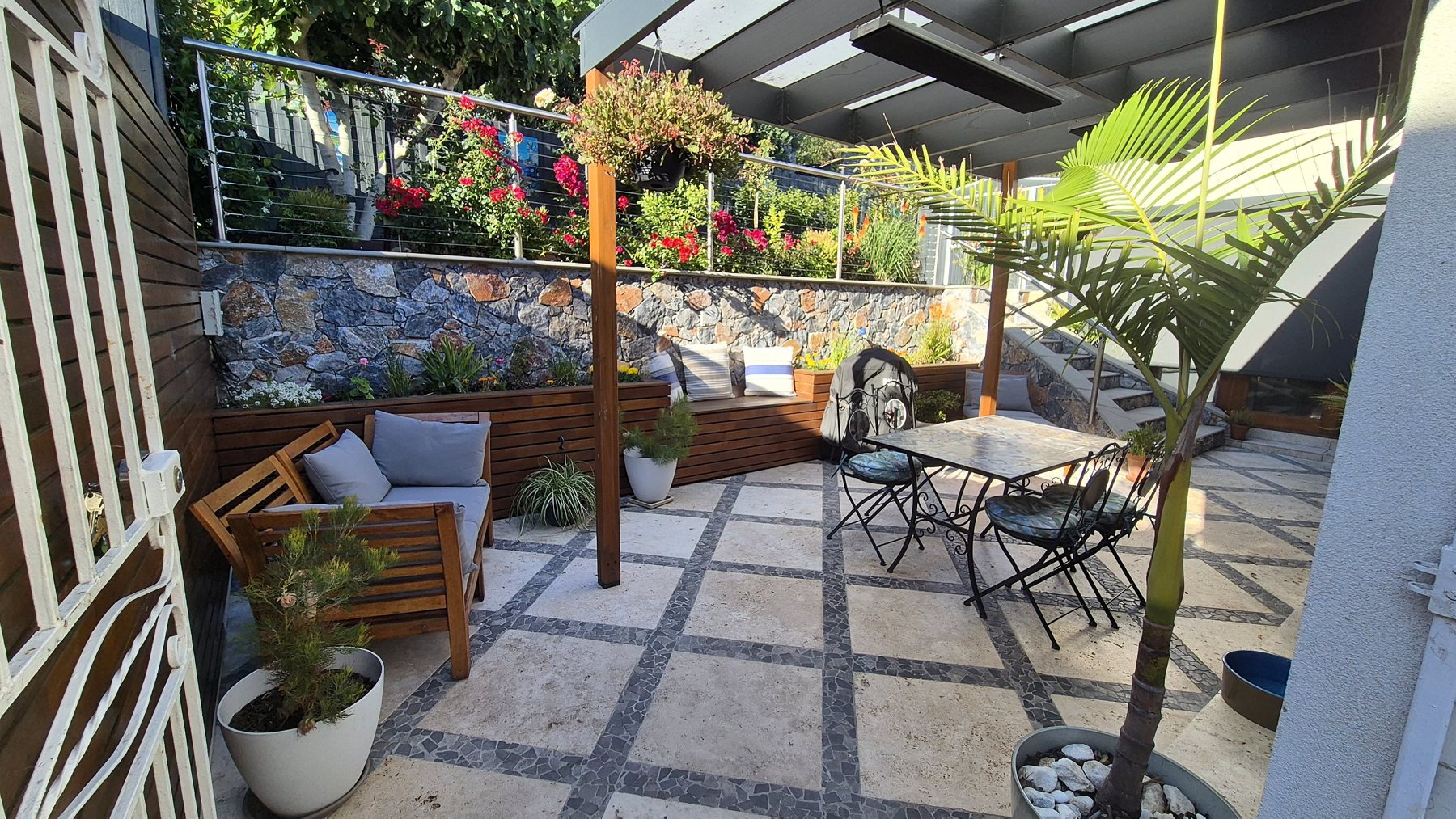 Courtyard seen through the gate, with timber benches and a natural stone wall