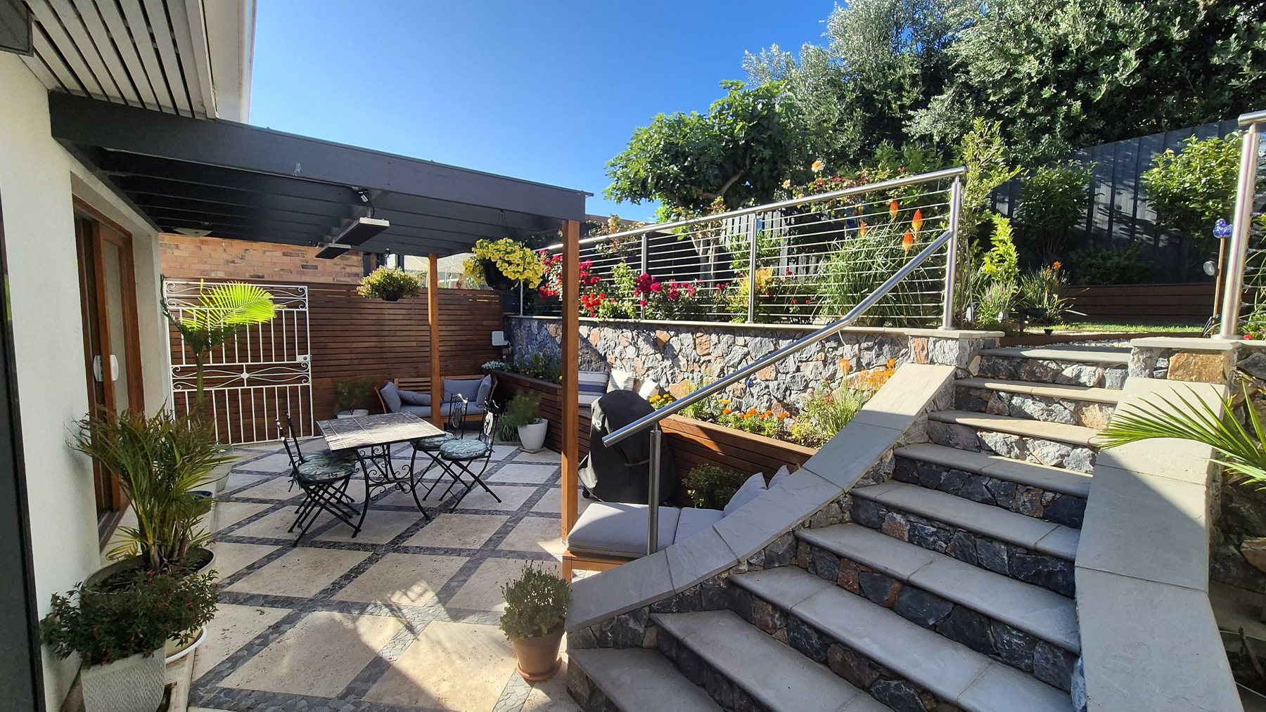 Travertine courtyard with mosaic bands, stone-clad stairs and a stainless cable balustrade
