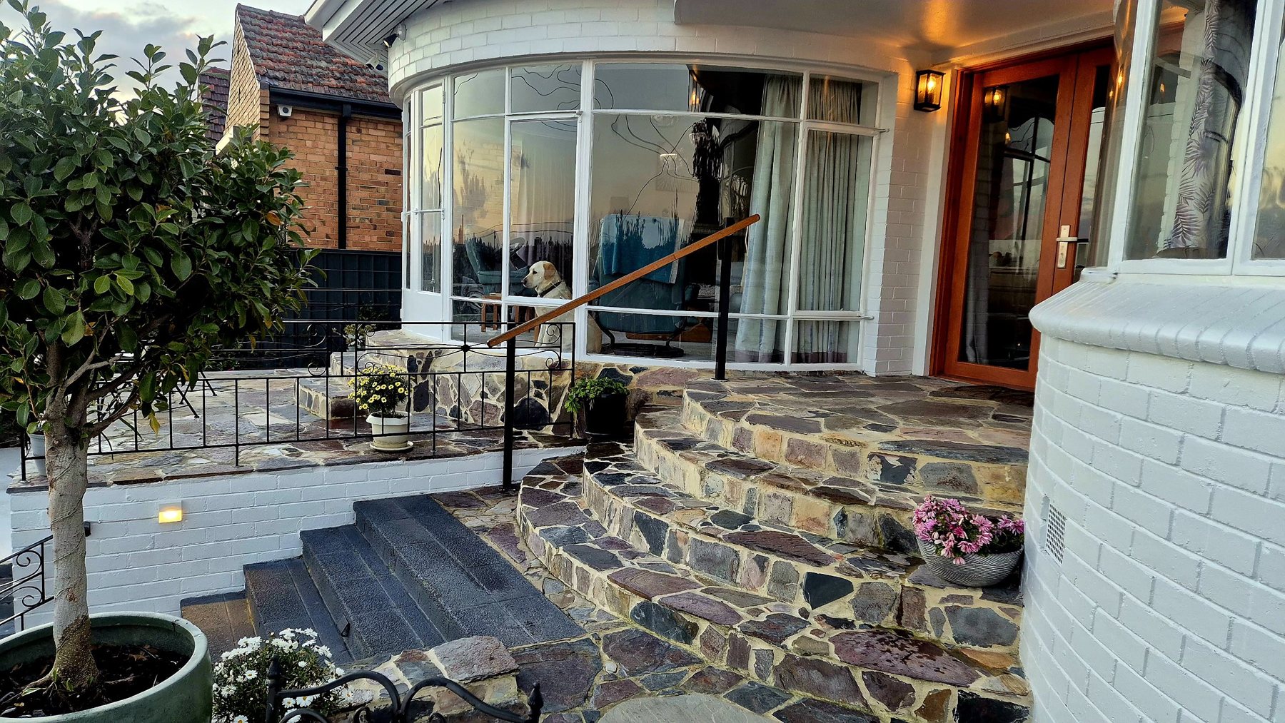 Curved natural stone entry steps up to an Art Deco front door