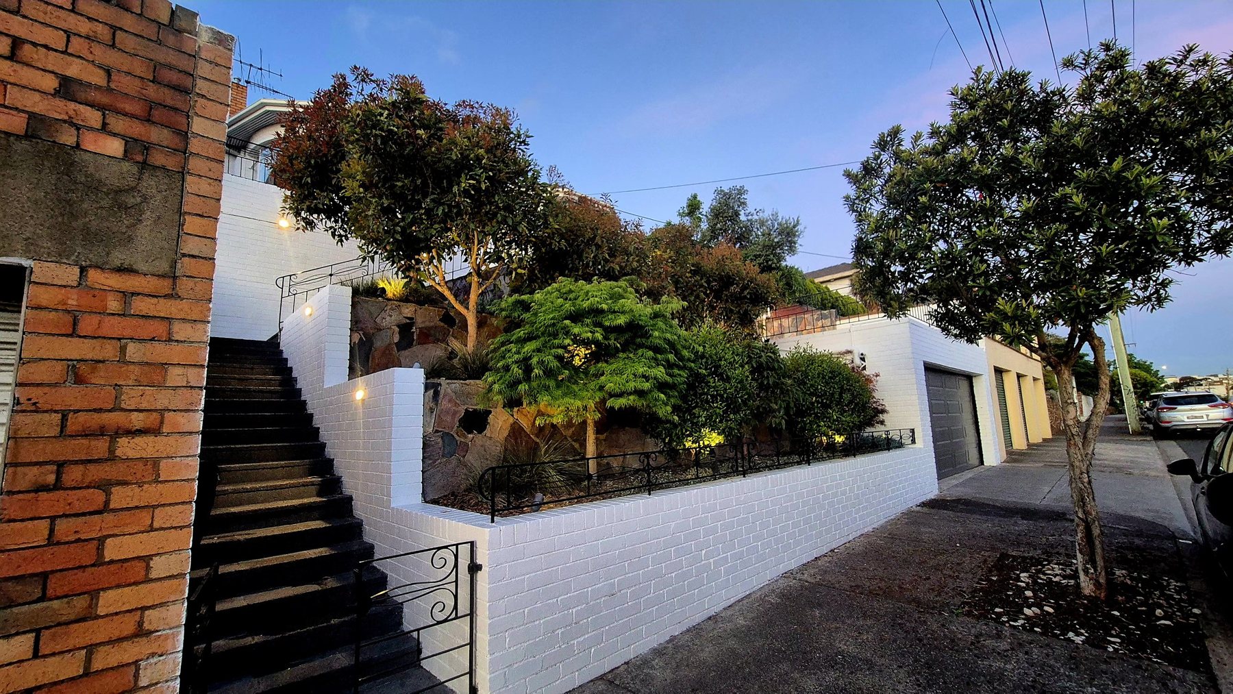 Front stairs, white brick walls and terraced planting at dusk