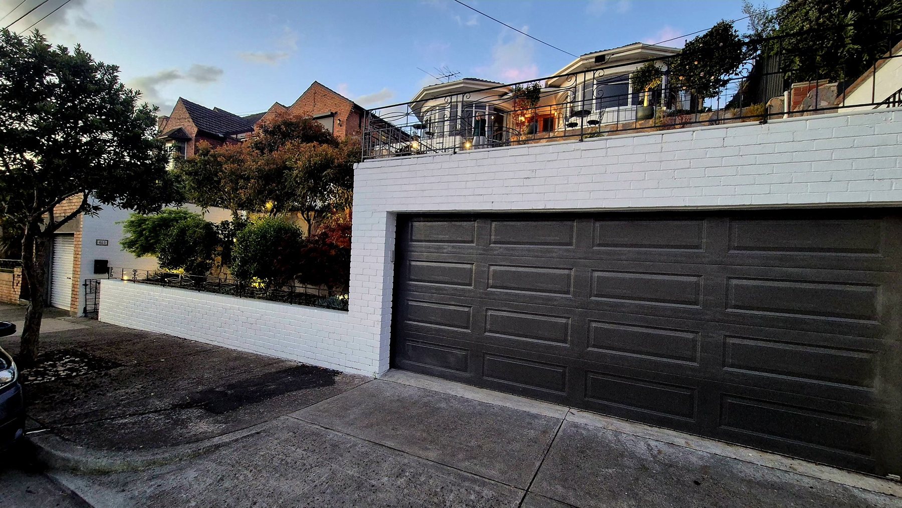 White brick front wall, garage and terraced garden above