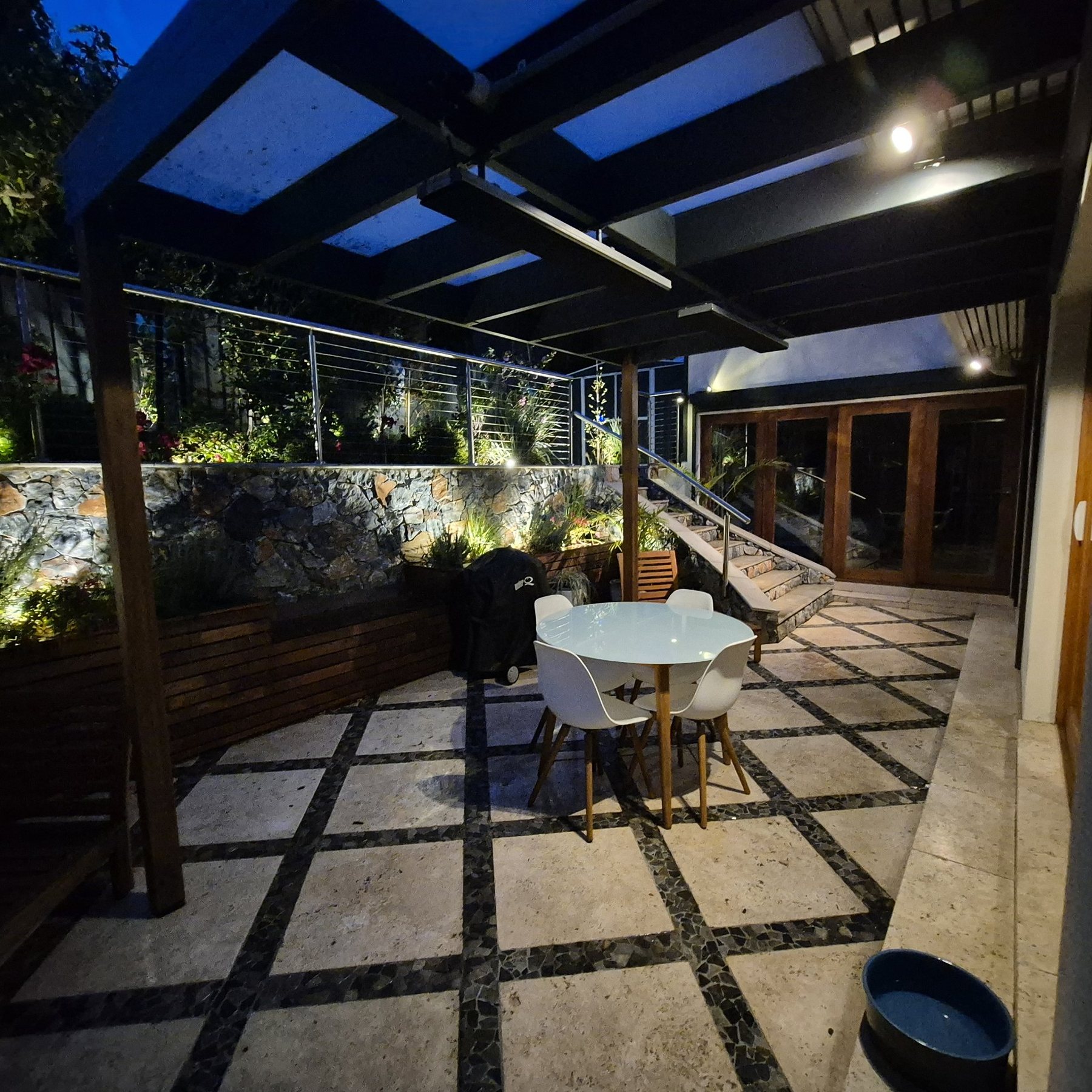 Travertine courtyard under a lit pergola at night