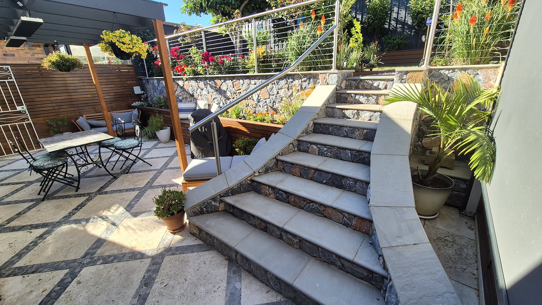 Curved stone-clad stairs with stone treads rising from the travertine courtyard
