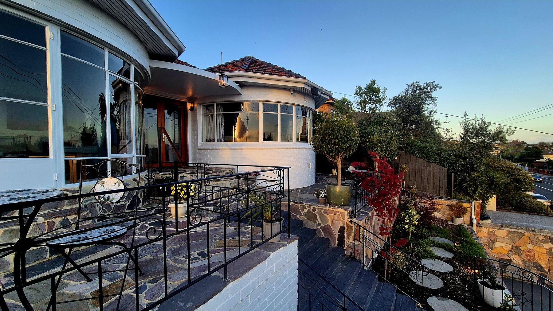 Art Deco house with flagstone terraces, iron balustrades and a red maple