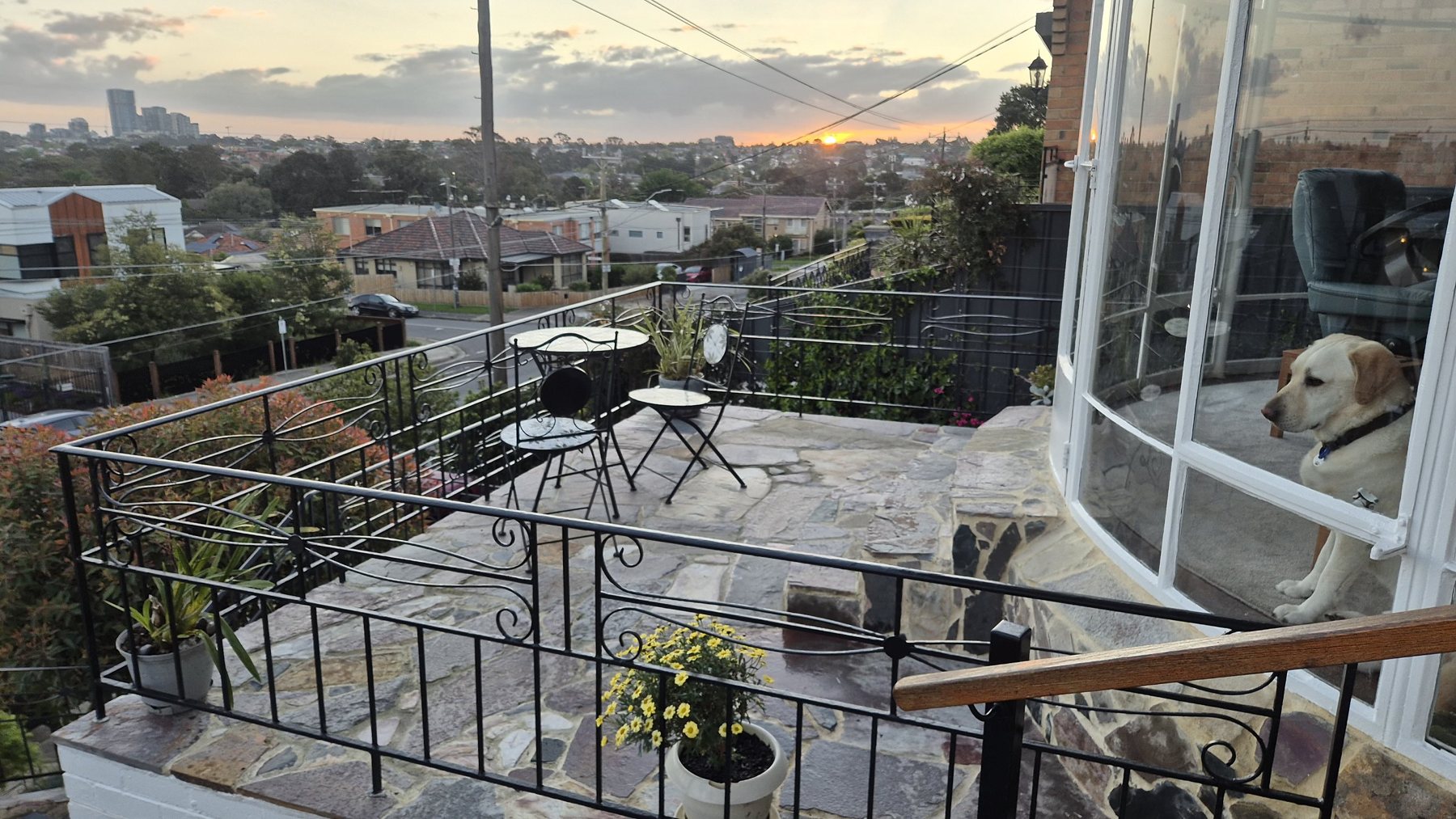 Flagstone terrace with iron balustrade at sunset over the suburbs