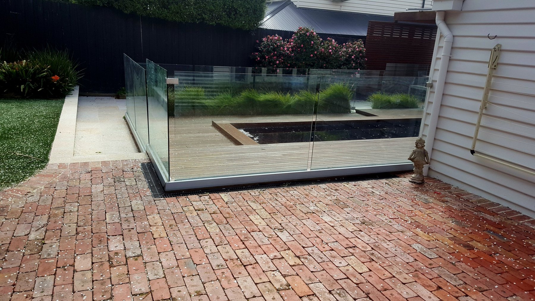 Brick paving running up to the glass pool fence