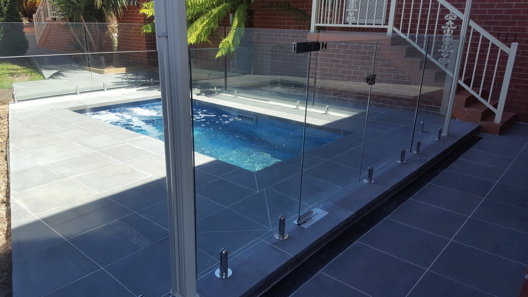 Dark stone pool surround with frameless glass