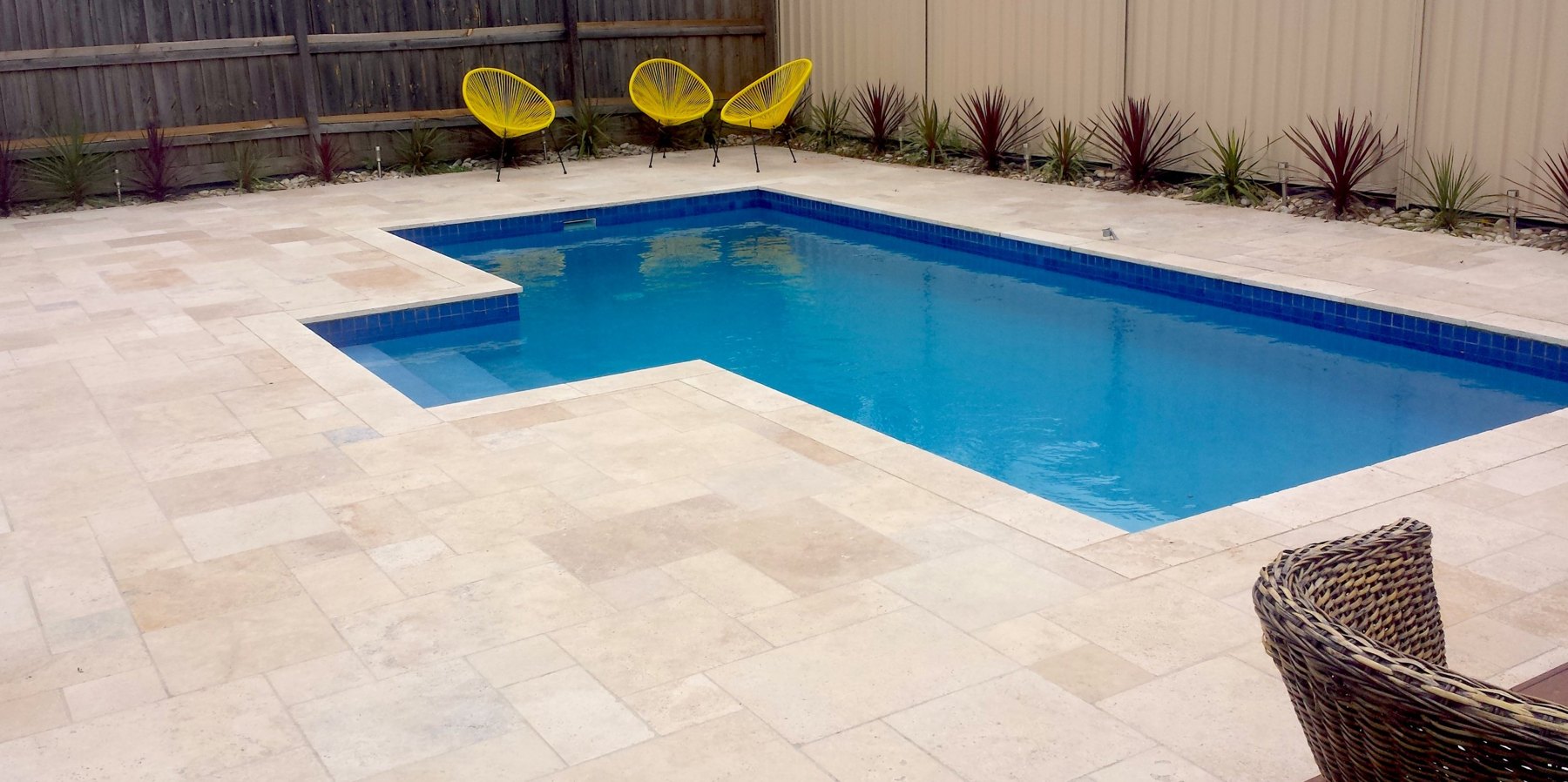 L-shaped pool in natural stone paving