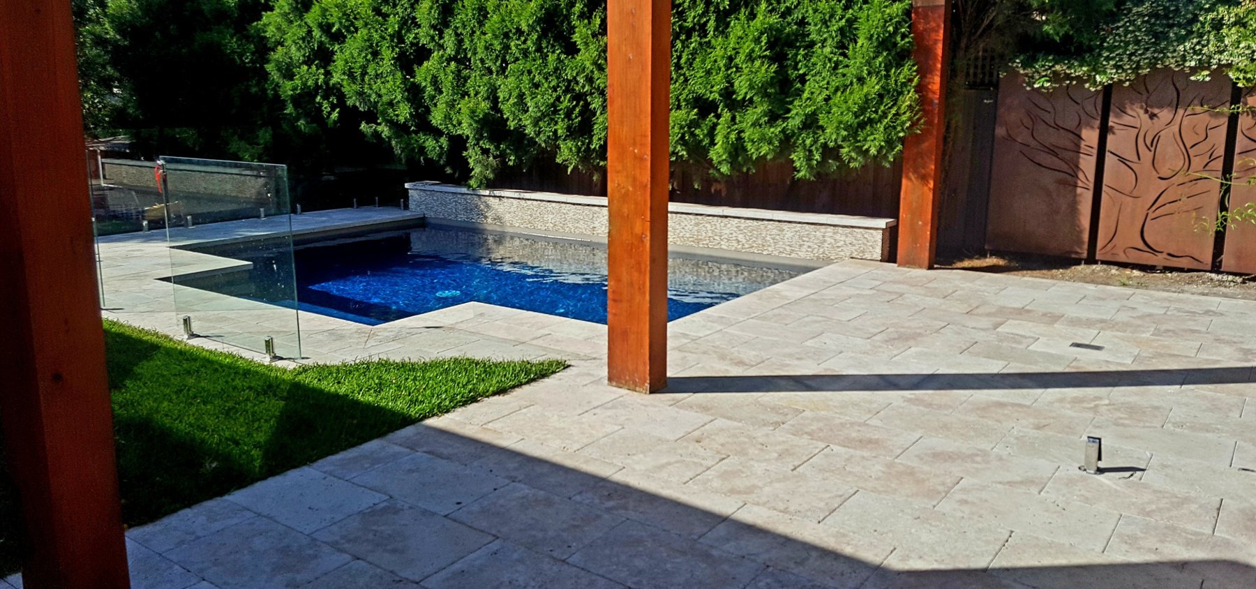 Natural stone paving between timber posts beside the pool