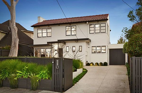 Front garden with a black timber fence, layered planting and buxus along the driveway